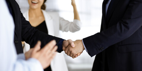 Unknown businesspeople are shaking their hands after signing a contract at meeting, close-up. Business communication concept