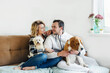 © Tatsiana - Happy young couple hugs two cute dogs sitting on the sofa. The youth way of life, the concept of home and animals.