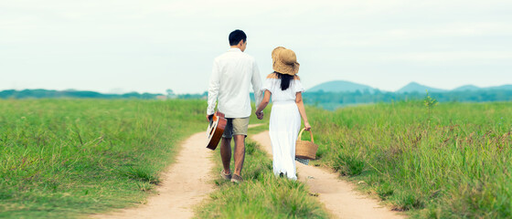 Lifestyle couple picnic sunny time. Asian young couple having fun and walking relax in the meadow and field in holiday.  Romantic and In love. 