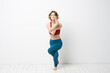 © SHOTPRIME STUDIO - sports woman in a bright room doing yoga in full growth blue leggings and a red tank top