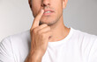 © New Africa - Man with herpes touching lips against light grey background, closeup