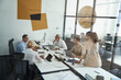 © Kostiantyn - Group of multiracial business people sharing ideas and discussing project while having a meeting in conference room, working together in the modern office