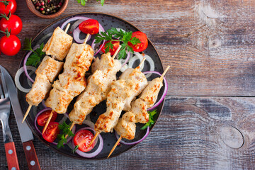 Wall Mural - Chicken breast skewers baked in the oven on wooden skewers on a plate, horizontal, copy space