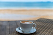 Latte art coffee cup on table near beach