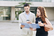 © DragonImages - Serious young entrepreneurs standing outdoors with coffee cups and reading documents in folder together