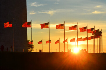 Silhouettes and U.S. national flags at Washington Monument grounds during sunset - Washington D.C. Unied Staes of America