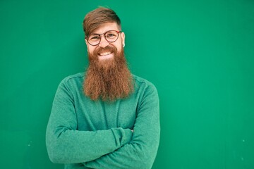 Sticker - Young irish man with arms crossed and smiling happy leaning on the wall at the city.