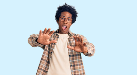 Poster - Handsome african american man with afro hair wearing casual clothes and glasses afraid and terrified with fear expression stop gesture with hands, shouting in shock. panic concept.