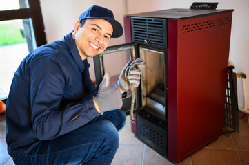 Wall Mural - Smiling technician maintaining a pellet stow heater and showing thumbs up