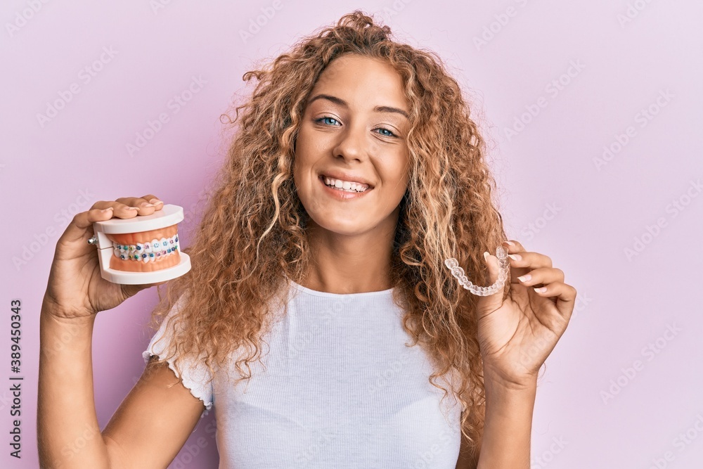 Beautiful caucasian teenager girl holding invisible aligner orthodontic and braces smiling with a happy and cool smile on face. showing teeth. - obrazy, fototapety, plakaty 