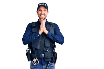 Canvas Print - Young handsome man wearing police uniform praying with hands together asking for forgiveness smiling confident.