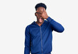 © Krakenimages.com - Young african american man wearing sportswear peeking in shock covering face and eyes with hand, looking through fingers with embarrassed expression.