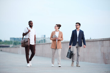 Poster - Three young intercultural business partners moving down road in front of camera