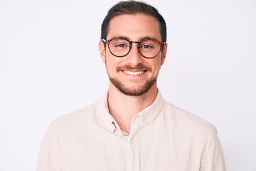 Wall Mural - Young handsome man wearing casual clothes and glasses looking positive and happy standing and smiling with a confident smile showing teeth