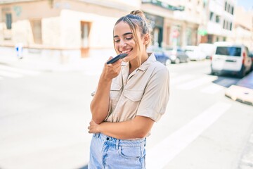 Wall Mural - Young beautiful blonde caucasian woman smiling happy outdoors on a sunny day using smartphone