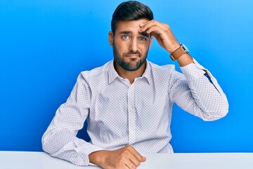 Sticker - Handsome hispanic man wearing business clothes sitting on the table worried and stressed about a problem with hand on forehead, nervous and anxious for crisis