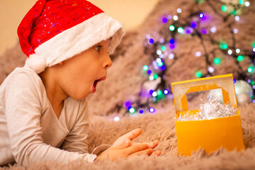 Wall Mural - child in santa claus hat surprised at gifts