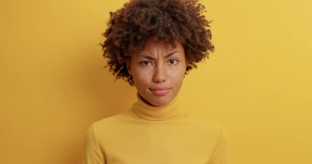 Wall Mural - Dissatisfied dark skinned woman with Afro hair smirks face and says no looks displeased cant believe in situation mistrusts person telling lies wears casual turtleneck isolated on yellow background