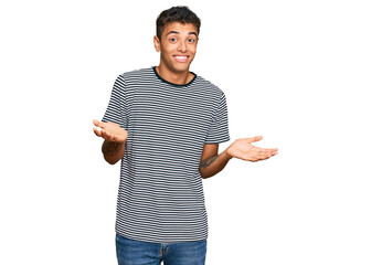 Canvas Print - Young handsome african american man wearing casual clothes clueless and confused expression with arms and hands raised. doubt concept.