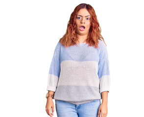 Young latin woman wearing casual clothes in shock face, looking skeptical and sarcastic, surprised with open mouth