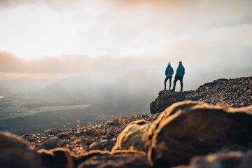 couple travelers man and woman standing on cliff relaxing mountains and clouds aerial view love and 