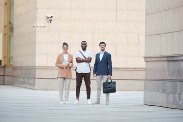 Poster - Young intercultural business partners in smart casualwear standing against wall