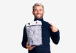 © Krakenimages.com - Young handsome blond man holding paper bin with crumpled papers pointing finger to one self smiling happy and proud