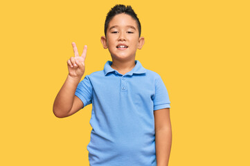 Sticker - Little boy hispanic kid wearing casual clothes smiling looking to the camera showing fingers doing victory sign. number two.