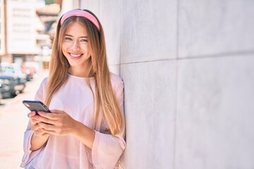 Young caucasian girl smiling happy using smartphone leaning on the wall.