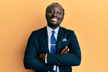 Sticker - Handsome young black man wearing business suit and tie happy face smiling with crossed arms looking at the camera. positive person.