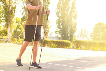 Young man training with walking poles outdoors