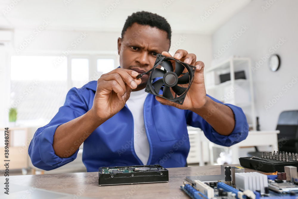 African-American technician repairing computer in service center