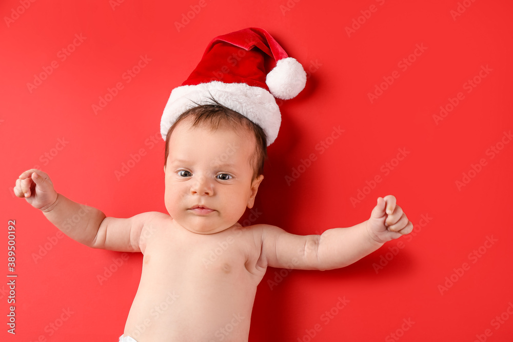 Cute little baby in Santa hat on color background