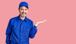 © Krakenimages.com - Middle age handsome man wearing mechanic uniform smiling cheerful presenting and pointing with palm of hand looking at the camera.
