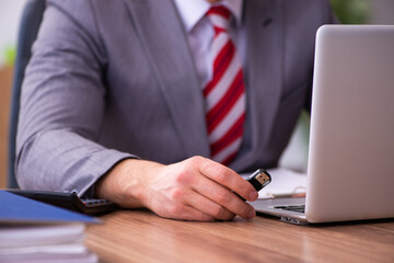 Young male employee inserting flash drive into laptop