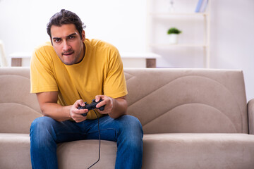 Wall Mural - Young man playing joystick games at home