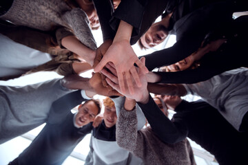 Wall Mural - bottom view. group of happy young people making a tower out of their hands .