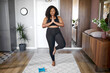 © Roman - young african black woman keep balance, stand on one leg, yoga time at home. concentrated on yoga, meditation