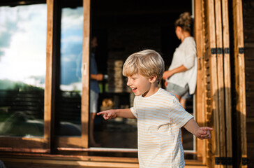 Wall Mural - small boy with parents on patio of wooden cabin, holiday in nature concept.