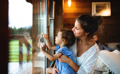 Wall Mural - small girl with parents in wooden cabin, holiday in nature concept.