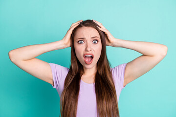 Wall Mural - Photo portrait of stressed woman keeping head with both hands staring with opened mouth isolated on vibrant teal color background