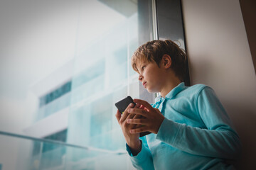 Wall Mural - Boy looking outside while staying home with mobile phone, social distancing challenges