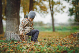 Fototapeta  - child sitting on a tree stump in the autumn forest