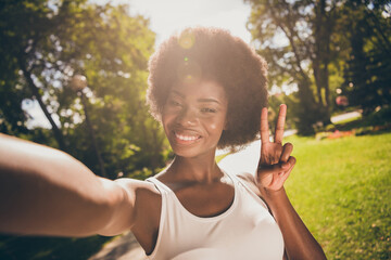 Sticker - Photo portrait of shiny woman shooting selfie in sunshine making v-sign outdoors