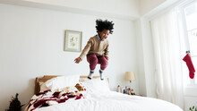 Young Kid Having A Fun Time Jumping On The Bed