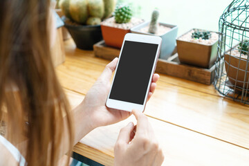 Hands of Asian girl using mobile phone on wooden table in cafe. Top view, copy space.