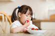 © M-image - young girl eating strawberry against real kitchen background