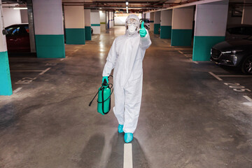 Wall Mural - Full length of man in sterile suit disinfecting hall of the building. Protection from corona concept.