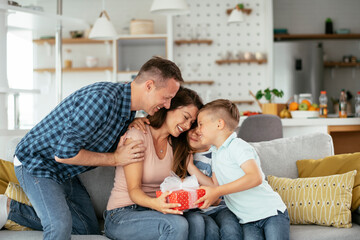 two young sons are giving their mother a gift. mother is suprised to receive a present from sons...