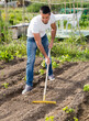 © JackF - Young man gardener with rake working at land in garden outdoor